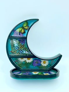 an artistic glass sculpture with flowers and butterflies on it's side, sitting in front of a white background