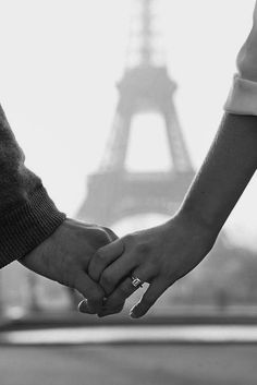 two people holding hands with the eiffel tower in the backgrounnd