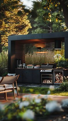 an outdoor kitchen with grill, table and chairs next to it in the grass near trees