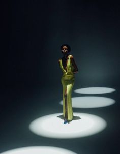 a woman standing in the middle of a dark room with white circles on the floor