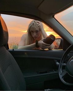 a woman sitting in the driver's seat of a car looking at her cell phone