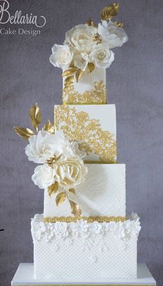 a three tiered wedding cake with white and gold flowers