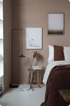 a bed room with a neatly made bed and two pictures on the wall above it