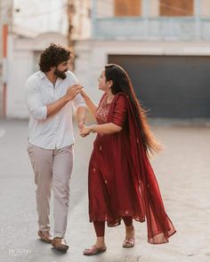 a man and woman standing next to each other in an empty parking lot holding hands