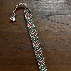 a green and red beaded tie sitting on top of a wooden table