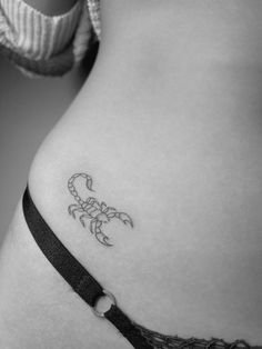 a small scorpion tattoo on the side of a woman's stomach is shown in black and white