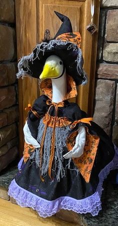 a stuffed duck dressed as a witch sitting in front of a door