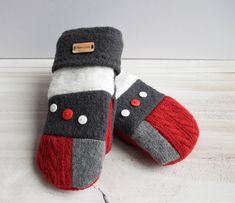 pair of gray and red slippers sitting on top of a white wooden floor next to a wall