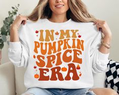 "In My Pumpkin Spice Era" Sweatshirt Step into fall with a cozy style in our "In My Pumpkin Spice Era" sweatshirt. This sweatshirt celebrates the ultimate autumn trend with a fun and playful twist, perfect for those who embrace the pumpkin spice season with enthusiasm. Key Features: The sweatshirt features the phrase "In My Pumpkin Spice Era" in a trendy, eye-catching font. The design is complemented by subtle autumn-themed accents like pumpkin illustrations or spice motifs, capturing the essenc Pumpkin Illustration, Pumpkin Spice Shirt, Thanksgiving Sweatshirt, Autumn Trends, Pumpkin Spice Season, Cozy Style, Cozy Fashion, Cozy Fall, Pumpkin Spice