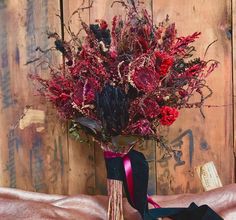 a vase filled with red flowers sitting on top of a bed