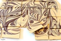 several pieces of brown and white chocolate on a white surface with squares cut out to look like swirls