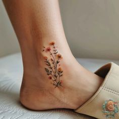 a woman's foot with flowers tattooed on the bottom of her leg and an orange flower