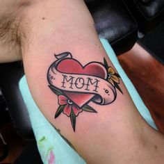 a tattoo on the arm of a man with a heart and ribbon that says mom