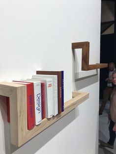 a couple of books that are sitting on a shelf in front of a man standing next to them