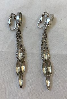 "Offering a pair of vintage earrings with four larger rhinestones at the bottom in a diamond pattern, and one large rhinestone at the top where the clip on is. In great condition, the earrings were created by Weiss.  Measures approximately 3\" in length. The Vintage Crate:  Located in Arnprior, Ontario, serving worldwide. Interested in more unique items, check out https://www.etsy.com/shop/TheVintageCrateTVC" Vintage Metal Crystal Earrings For Party, Vintage Jeweled Dangle Crystal Earrings, Silver Jeweled Clip-on Earrings, Formal Metal Earrings With Rhinestones, Formal Metal Crystal Earrings With Rhinestones, Formal Crystal Rhinestone Metal Earrings, Formal Crystal Rhinestone Earrings, Vintage Silver Jeweled Crystal Earrings, Vintage Rhinestone Crystal Earrings For Party