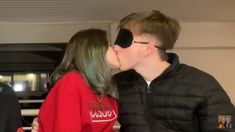 a man and woman kissing each other while wearing blindfolds