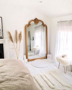 a bedroom with a large mirror and white rugs on the floor in front of a fireplace