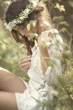 a woman is sitting in the grass with her hand on her face and looking down