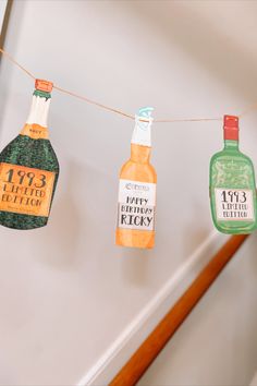 some bottles are hanging from a clothesline with paper tags attached to them that say happy new year