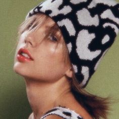 a woman wearing a black and white hat with an animal print pattern on the top