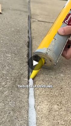 a person is painting the side of a sidewalk with yellow and white paint on it