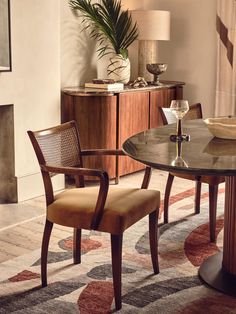 a dining room table with two chairs and a vase on top of it next to a fireplace