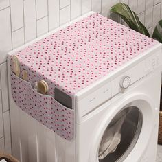 a washing machine with a pink and red polka dot cover on the front, sitting next to a white tiled wall