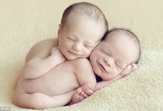 two babies cuddle together on a blanket