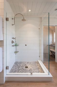 a walk in shower sitting next to a white towel on a rack and wooden floor