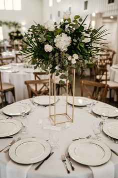 a table with white plates and silverware is set up for a formal dinner party