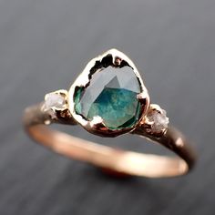 a close up of a ring with an aqua and white stone in the center, on a black surface