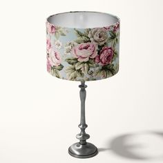 a lamp shade with pink roses on blue and white fabric is shown in front of a white background