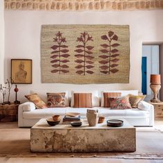 a living room filled with furniture and a large tapestry hanging on the wall above it