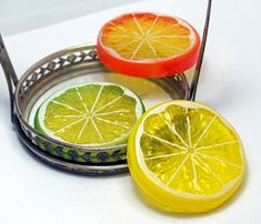 two oranges and one lemon are sitting on a tray with tongs next to each other