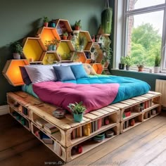 a bed made out of wooden pallets with colorful sheets and pillows on it in front of a window