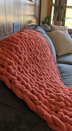 an orange knitted blanket sitting on top of a couch