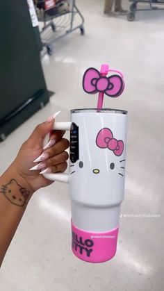 a person holding up a hello kitty coffee cup with a straw sticking out of it