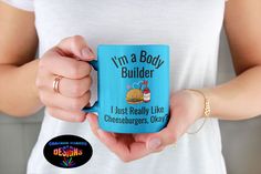 a woman holding a blue coffee mug with the words i'm a body builder on it