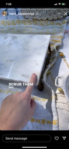 someone is pointing at the white marble on top of a tablecloth that says scrub them off