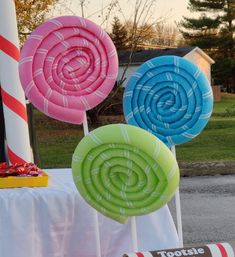 three lollipops are on sticks in front of a table with candy canes