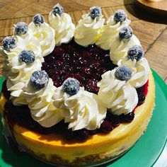 a cake with white frosting and blueberries on top sitting on a green plate