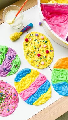 colorful cookies are on the table with paint and sprinkles