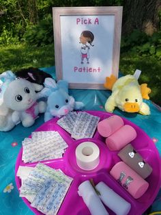 two stuffed animals sitting on top of a purple tray next to a sign that says pick a patient