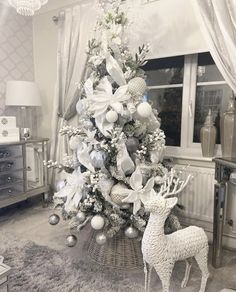 a white christmas tree with silver ornaments in a living room