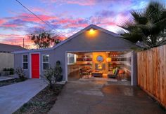 a house with a red door and palm tree in the front yard at sunset or dawn