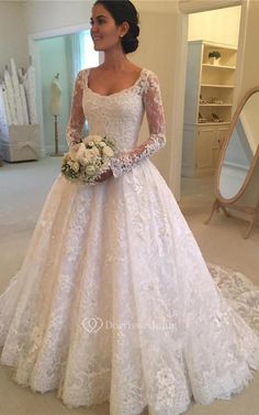 a woman in a white wedding dress standing next to a mirror and looking at the camera