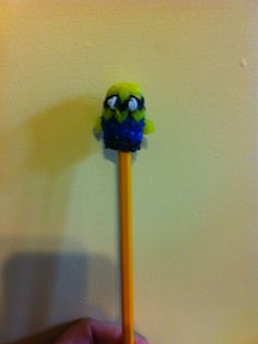 a pencil with an angry face on it sitting in front of a yellow wall next to a person's hand