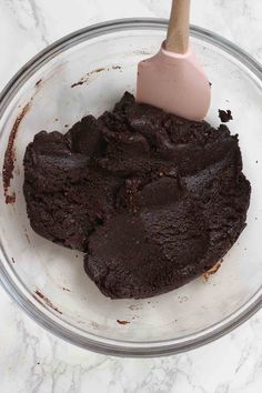 a bowl filled with brownie batter and a pink spatula on top of it