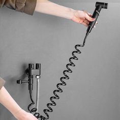 a person is holding a hair dryer in front of a wall mounted hose holder