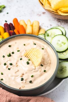 a bowl filled with dip surrounded by vegetables and chips